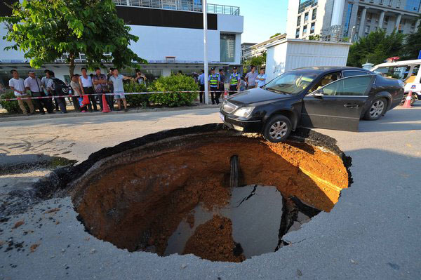 Sinkhole blocks road, damages 2 cars